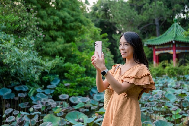 Mulher usa telefone celular para tirar foto no jardim