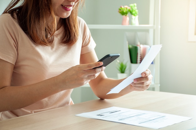 Mulher usa um smartphone para escanear o código de barras para pagar contas telefônicas mensais após receber uma fatura enviada para casa