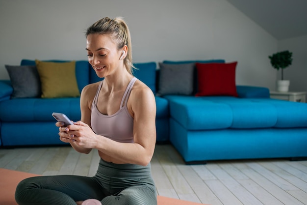 Mulher usando airpods e um smartphone durante o treino em casa