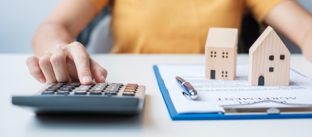 Mulher usando calculadora durante a assinatura de documentos de contrato em casa Contrato de compra e venda de imóveis e conceitos de seguro