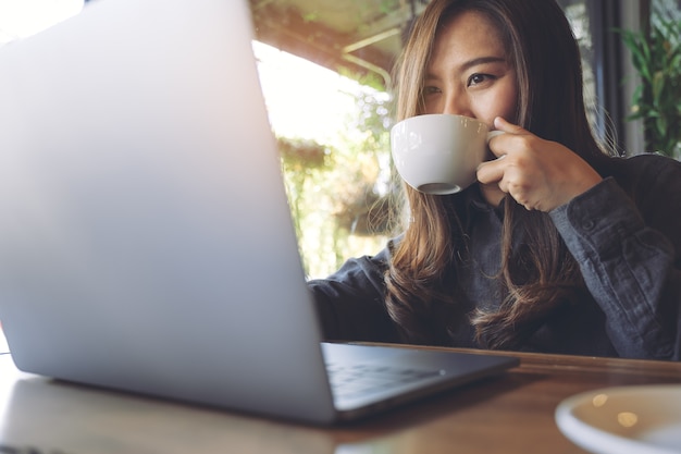 Mulher, usando computador, laptop, com, xícara café