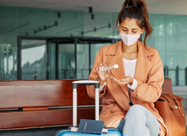 Foto mulher usando desinfetante para as mãos no aeroporto durante a pandemia