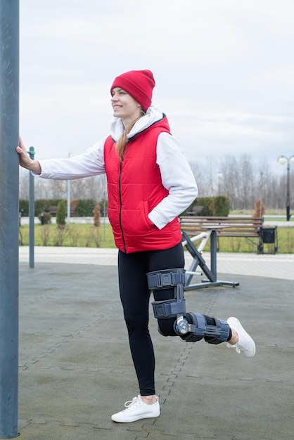 Mulher usando joelheira ou órtese após cirurgia na perna malhando no parque