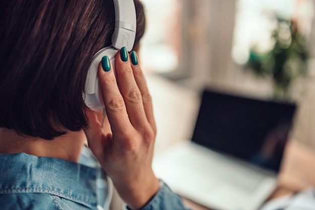 Mulher usando laptop e ouvir música em um fone de ouvido