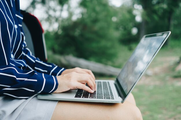 Mulher usando laptop e smartphone para trabalhar estudo de férias na praia.