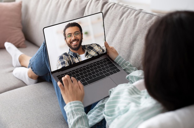 Mulher usando laptop em casa para bate-papo por vídeo com o namorado indiano