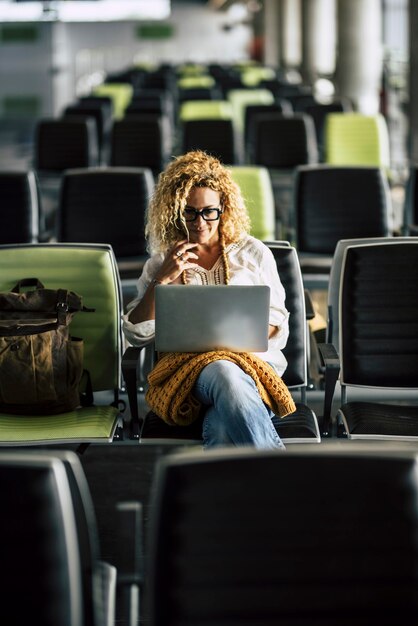 Foto mulher usando laptop enquanto está sentada no aeroporto
