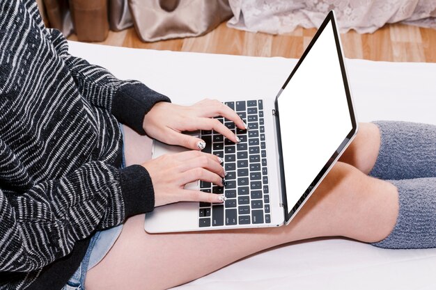 Mulher usando laptop na cama branca em casa