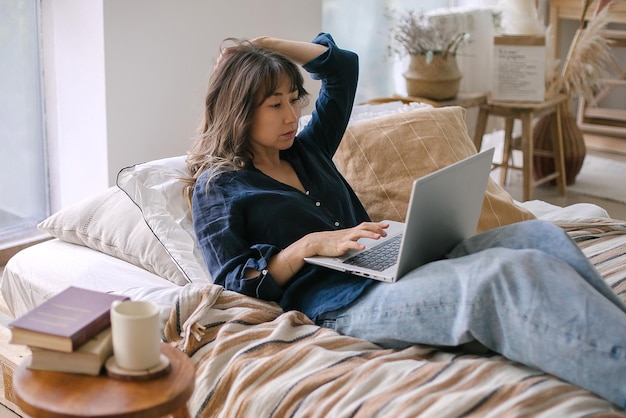 Mulher usando laptop na cama em casa