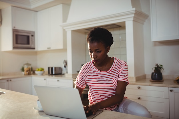 Mulher usando laptop na cozinha