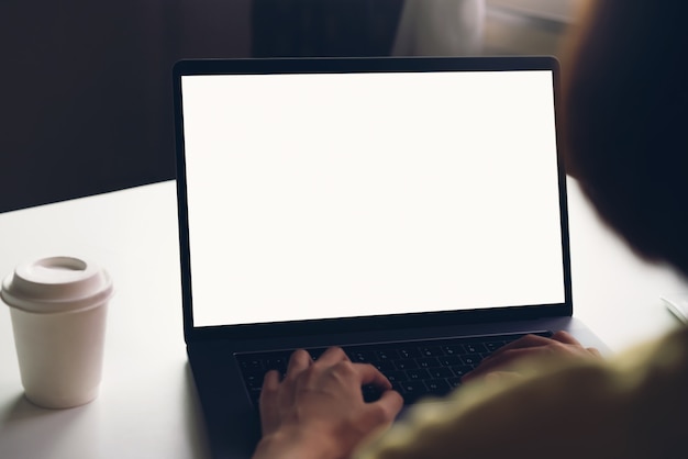 Mulher usando laptop na mesa, simulado acima da tela em branco.