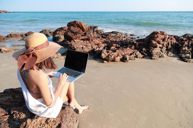 Foto mulher usando laptop na praia