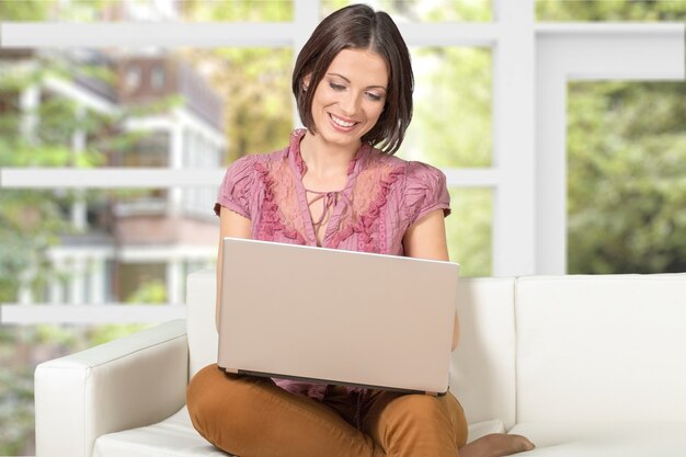Mulher usando laptop no sofá em casa