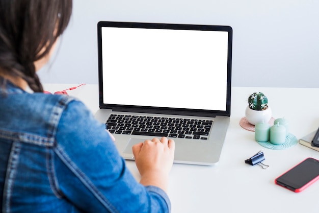 Mulher usando laptop perto de smartphone na mesa