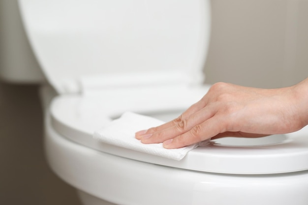 Mulher usando lenço de papel limpa o banheiro no banheiro em casa