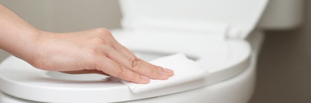 Mulher usando lenço de papel limpa o banheiro no banheiro em casa