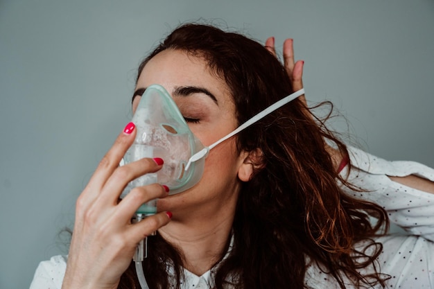 Foto mulher usando máscara de oxigênio contra um fundo cinzento
