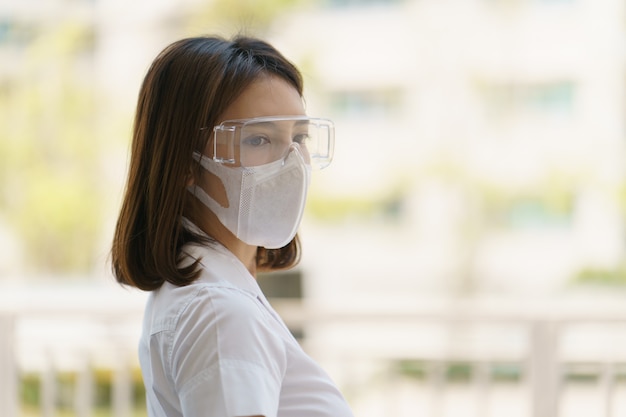 Mulher usando máscara e óculos de segurança, para evitar a propagação do coronavírus.
