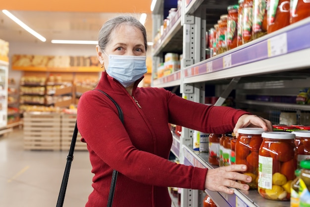 Mulher usando máscara facial comprando e escolhendo produtos no supermercado