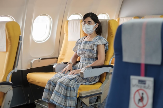 Mulher usando máscara facial protetora sentada em avião ou transporte público, proteção contra infecção por doença de coronavírus, turista pronto para viajar. Próximo Normal, turismo e conceito de reabertura