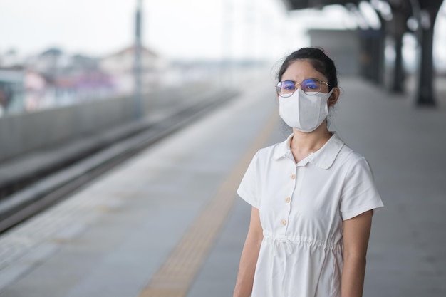 Mulher usando máscara protetora de prevenção de coronavírus e poluição PM 2.5 durante a espera do trem. transporte público. segurança sob a pandemia covid-19 e poeira