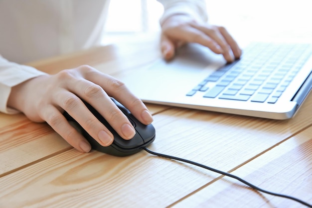 Mulher usando mouse de computador com laptop na mesa de madeira