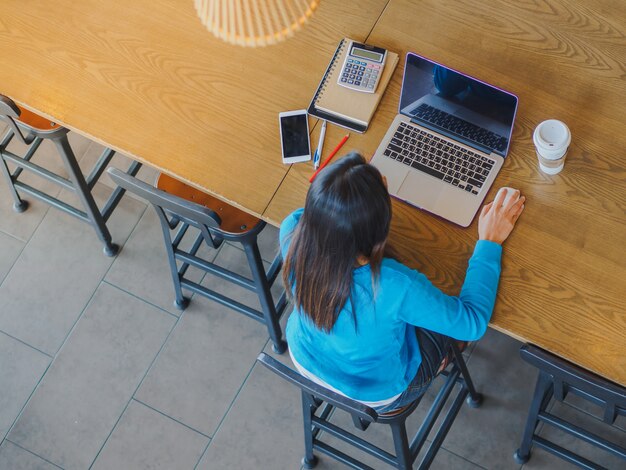 Mulher usando o computador portátil. Fêmea trabalhando no laptop no café.