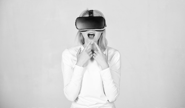 Foto mulher usando óculos de realidade virtual em fundo cinza jovem espantada tocando o ar