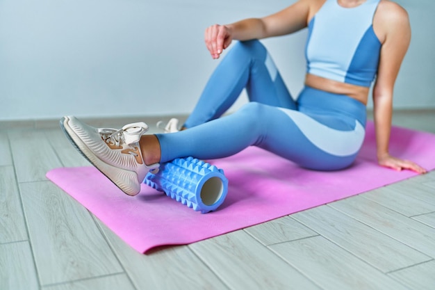 Mulher usando rolo para auto massagem muscular