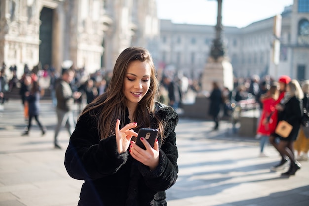 Mulher usando seu smartphone enquanto caminha por uma cidade europeia