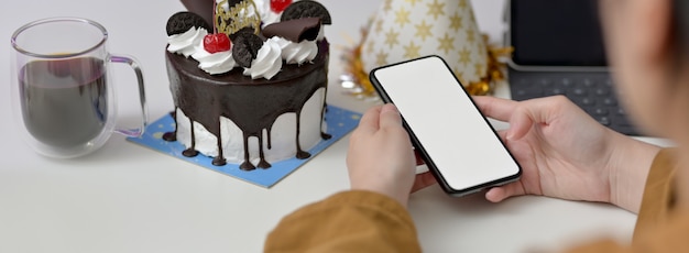 mulher usando smartphone com bolo