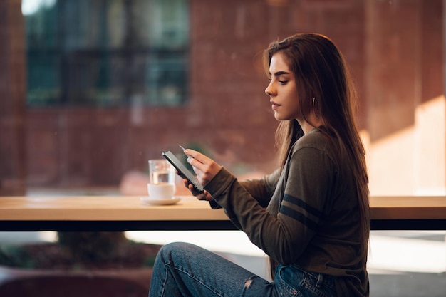 Mulher usando smartphone e cartão de crédito para compras online em um café