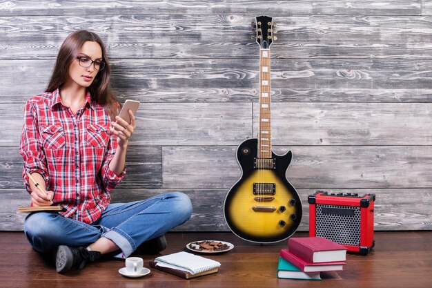 Mulher usando smartphone e escrevendo no bloco de notas