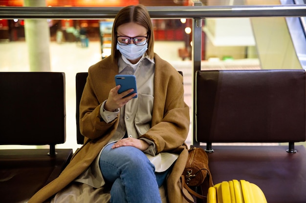 Mulher usando smartphone enquanto está sentada na sala de espera
