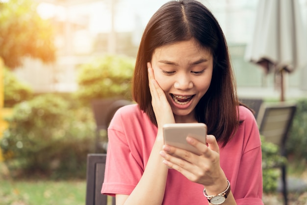 Mulher usando smartphone para a aplicação na mesa no café do parque.