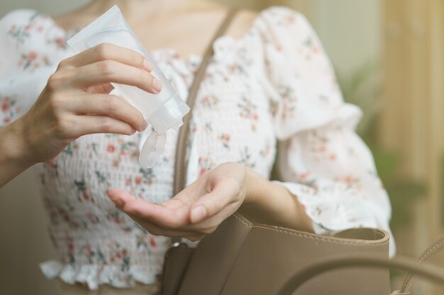 Mulher usando spray desinfetante para as mãos de sua bolsa de mão, prevenção do coronavírus.