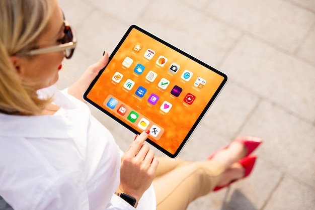 Mulher usando tablet com tela inicial colorida cheia de ícones de aplicativos de amostra