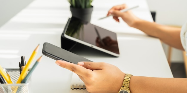 Mulher usando tablet digital e smartphone na mesa