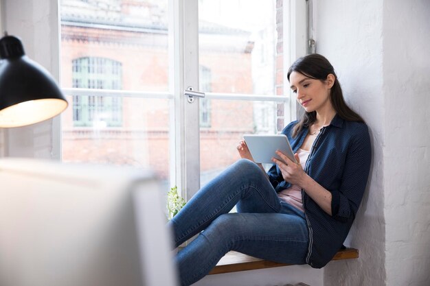 Mulher usando tablet na janela do escritório