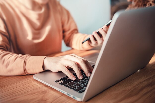 mulher usando telefone celular e laptop em casa