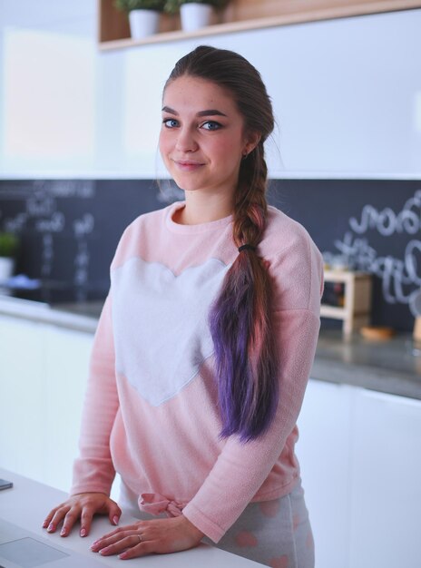 Mulher usando telefone celular em pé na cozinha moderna