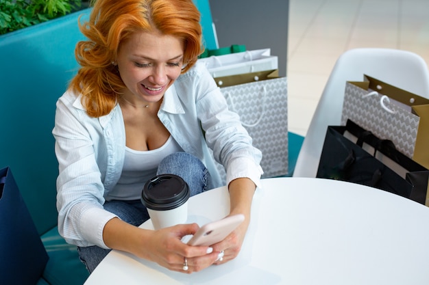 Foto mulher usando telefone celular enquanto bebia café no café no shopping