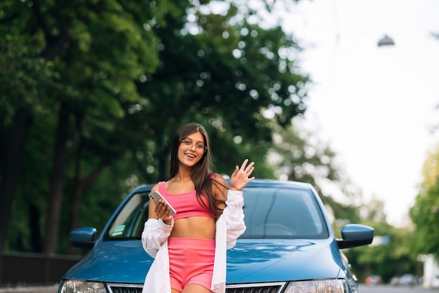 Mulher usando telefone celular perto de carro na rua