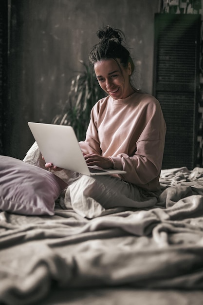 Mulher usando telefone enquanto está sentada na cama