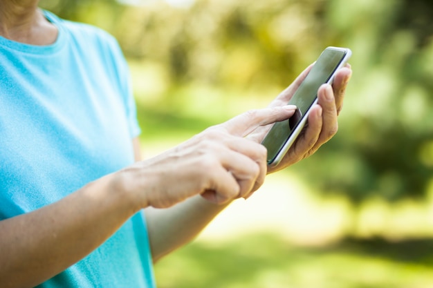 Mulher usando telefone inteligente com tela preta em branco no exterior