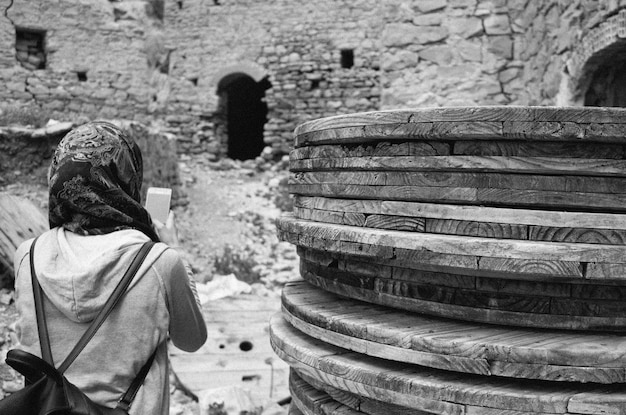 Foto mulher usando telefone inteligente enquanto está em frente à velha ruína