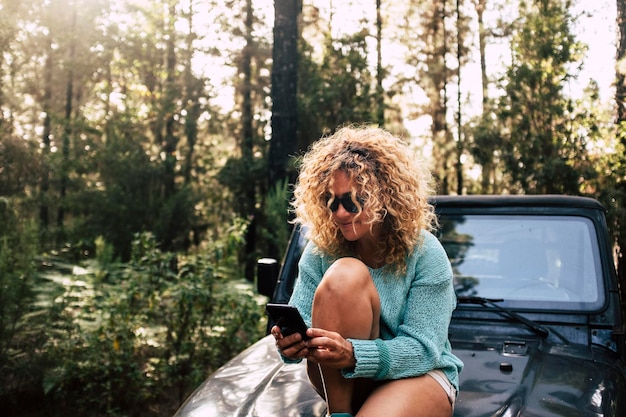 Foto mulher usando telefone móvel enquanto está sentada em um veículo na floresta