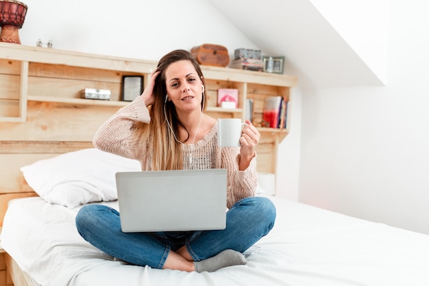 Mulher usando telefone móvel enquanto está sentada na cama em casa