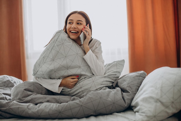 Mulher usando telefone na cama pela manhã