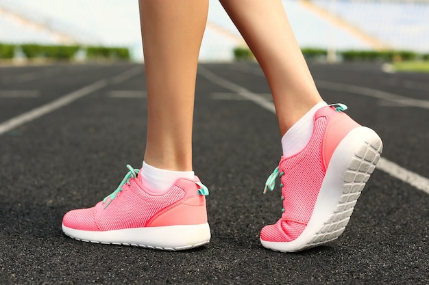 Mulher usando tênis rosa em um estádio de corrida